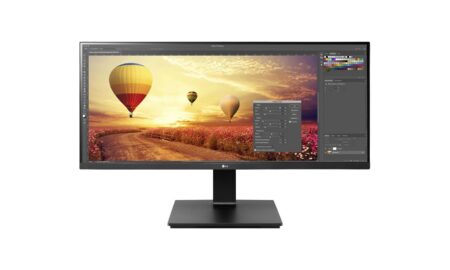 Ein breiter LG 34BR65F-B monitor für das büro auf einem hellen Holzschreibtisch mit Business-Anwendungen.