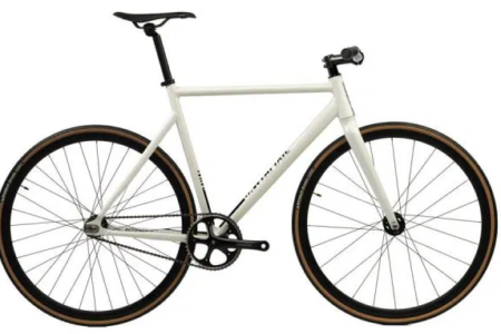 Ein sportliches santafixie raval Stadtrad in der Seitenansicht, fotografiert vor einem modernen urbanen Hintergrund.
