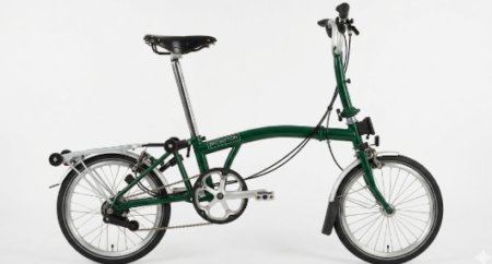 Ein elegantes brompton c line Klapprad in der Seitenansicht, perfekt gefaltet vor einem neutralen urbanen Hintergrund.