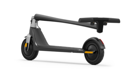 Ein hochwertiger unagi model one voyager E-Scooter in der Seitenansicht, fotografiert vor einer modernen urbanen Stadtkulisse.